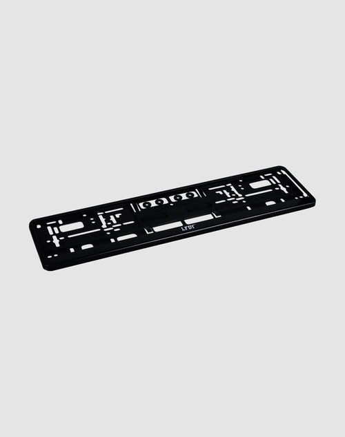 The LFDY License Plate Holder (2 Pack) by LIVE FAST DIE YOUNG is a black plastic Eurokennzeichen holder with multiple mounting slots and holes and a subtle LFDY logo, shown on a light gray background.