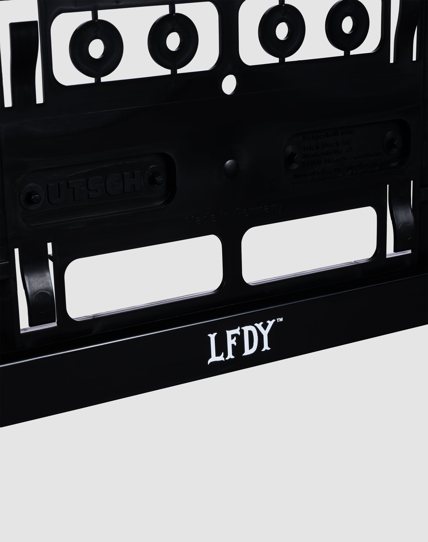 Close-up of the LFDY License Plate Holder (2 Pack) by LIVE FAST DIE YOUNG, featuring a bold white LFDY logo on a black frame for Euro license plates, displayed against a light gray background.