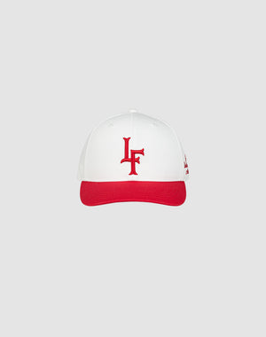 The LF Snapback by LIVE FAST DIE YOUNG features a white design with red brim, red LF logo embroidery on the front, made from 100% cotton and finished with a snapback closure, showcased against a simple light grey background.