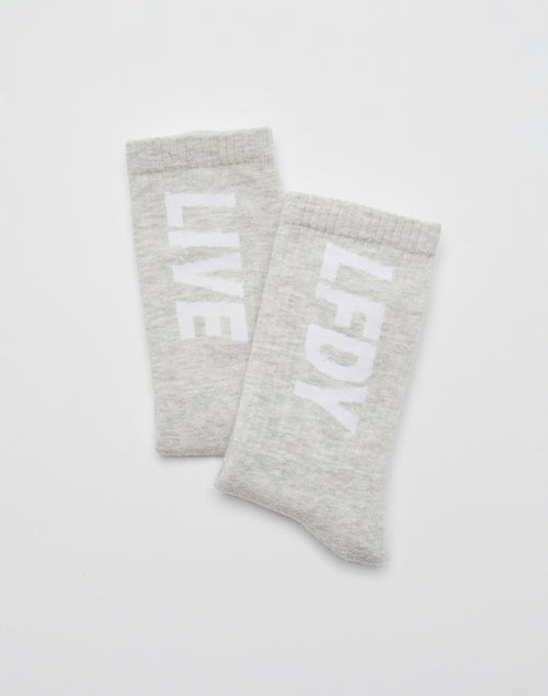 Two light gray Basic Typo Socks (2 Pack) from LIVE FAST DIE YOUNG, each with a bold white LIVE and LF DY logo arranged vertically, overlap on a plain white background.