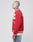 A person with short hair and neck tattoos wears the red LFDY OC College Jacket featuring cream stripes and Frottee-Patch lettering, paired with light jeans, posing in profile against a plain light background.