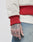 A close-up of a tattooed hand with a lion’s face and LIVE on the fingers, wearing blue jeans and an LFDY OC College Jacket in cream with red ribbed cuffs, waistband, and side pockets.