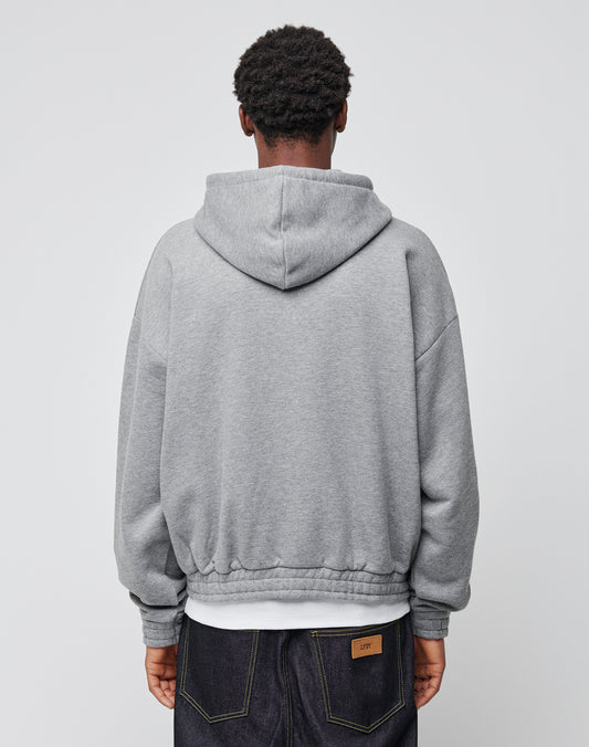 A person stands with their back to the camera, wearing a grey LFDY Hooded Zip sweatshirt with double-layer hood and dark jeans featuring visible stitching, set against a plain light grey background.