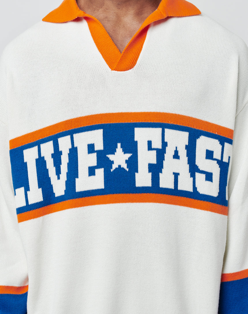 A person wears the LFDY Knit Polo by LIVE FAST DIE YOUNG, a white pullover with orange and blue trim, Polo collar, and bold blue and white "LIVE FAST" lettering across the chest.