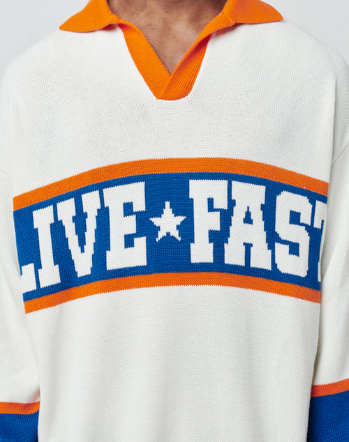 A person wears the LFDY Knit Polo by LIVE FAST DIE YOUNG, a white pullover with orange and blue trim, Polo collar, and bold blue and white "LIVE FAST" lettering across the chest.