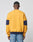 A person faces away wearing the LFDY® Sweater by LIVE FAST DIE YOUNG, an oversize mustard yellow sweatshirt with navy bands on the sleeves and waistband, crafted from comfortable Baumwolle fabric, paired with distressed blue jeans.
