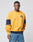 A man in an oversize fit LFDY® Sweater by LIVE FAST DIE YOUNG, featuring yellow fabric with navy blue accents on the sleeves and hem, and blue jeans, stands facing forward against a plain light gray background.