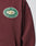 The Import & Export Hooded by LIVE FAST DIE YOUNG is a maroon oversized sweatshirt with a vintage effect, featuring a green and white chest patch reading “LIVE FAST IMPORT & EXPORT” with lemons and family business details since 2012.