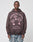 A man wears the LIVE FAST DIE YOUNG Wisdom Hooded—a dark, oversized cotton hoodie with pink parachute graphics and WISDOM WILL ARRIVE, Live Fast, and *0800 55 747 55 text, plus a vintage effect. He stands against a plain light background.
