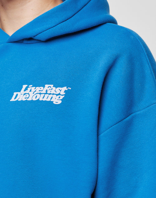 Close-up of a person wearing a bright blue Basic Chest Hooded by LIVE FAST DIE YOUNG, featuring the white Live Fast Die Young chestprint over the left chest area.