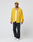 A man stands against a plain background, wearing the yellow LFDY Frottee Shirt by LIVE FAST DIE YOUNG in Oversize Fit over a white T-shirt, black ripped jeans, and white sneakers. The shirt is 100% Baumwolle. He faces forward with a neutral expression.