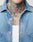 A close-up of a persons chest and neck wearing a LIVE FAST DIE YOUNG LFDY® Denim Shirt with a visible chest pocket, layered over a white ribbed tank top, showing colorful tattoos on their neck and upper chest.