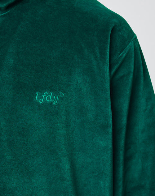 Close-up of the LIVE FAST DIE YOUNG Velvet Halfzip in green, featuring oversize fit and LfdY™ embroidery on the chest. The soft velvet shows part of the shoulder, sleeve, and upper chest.
