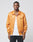 A man with short hair and a neutral expression models the LIVE FAST DIE YOUNG Satin College Jacket—an orange polyester button-up with striped cuffs, Loyalist embroidery, and a regular fit—against a plain light background.