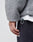 A close-up of a hand resting by the side, wearing LIVE FAST DIE YOUNGs Oversize Teddy Jacket in grey with a detailed drawstring and black pants. The jackets texture and oversized fit are clearly visible.