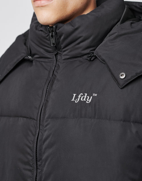 A close-up of a person wearing the Basic Winter Jacket by LIVE FAST DIE YOUNG. The black jacket features a high collar, visible zipper, silver snap buttons, and LFDY™ embroidered in white on the chest.