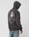 A man in the LIVE FAST DIE YOUNG Live Fast Skull Hooded, featuring a vintage-effect skull smoking a cigarette and “Liv Fast” on the back, pairs it with light blue jeans and faces away from the camera.