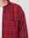 A person wears a LIVE FAST DIE YOUNG Padded Flannel Jacket with red and black plaid, zweiteiliger Hemdkragen, and oversize fit over a white t-shirt. Only the upper torso and part of the face are visible against a plain, light background.