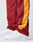 Close-up of a person wearing LIVE FAST DIE YOUNG LFDY Trackpants in red and yellow polyester, featuring elastic cuffs, color-block design, and a side zipper. Paired with classic white Nike Air Force 1 sneakers.