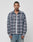 A man stands facing forward in the LIVE FAST DIE YOUNG Loose Flannel Shirt, featuring a gray and pink plaid vintage wash, layered over a white tee and blue jeans against a plain light background.