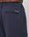 Close-up of the back and side of Regular Casual Pants by LIVE FAST DIE YOUNG in navy blue, featuring a welt back pocket with “LIVE FAST™” embroidered above it in white and an elastic waistband, worn by a person with medium brown skin.