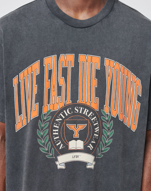 A person wears the Live Fast Die Young Tee by LIVE FAST DIE YOUNG, featuring an oversize fit, bold orange LIVE FAST DIE YOUNG text, a vintage bull head print with laurel leaves, and the words AUTHENTIC STREETWEAR and LFDY.