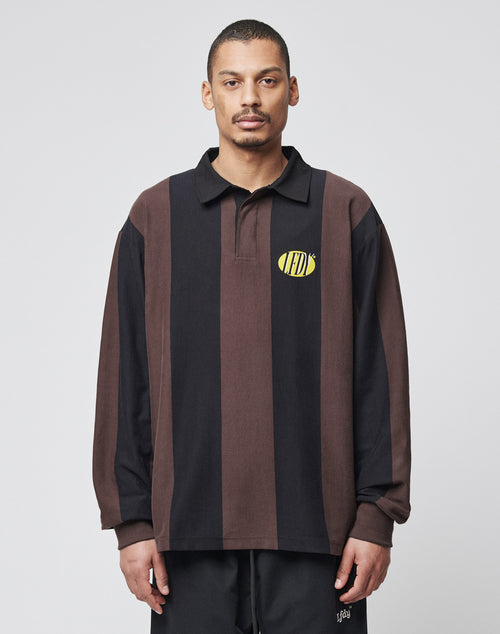 A man wears the LFDY® Polo Longsleeve by LIVE FAST DIE YOUNG, an oversized, 100% Baumwolle shirt with brown and black vertical stripes, Polokragen, and a yellow oval logo on the chest, standing against a light gray background.
