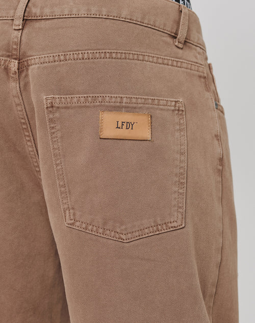 Close-up of the back pocket on Regular Denim pants by LIVE FAST DIE YOUNG, showing a tan leather patch with LFDY embossing. Made from 100% Baumwolle, these pants provide a Regular Fit for everyday comfort and style.