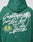 Person wearing the Live Fast Greetings Hooded by LIVE FAST DIE YOUNG, an oversize green hoodie with white script on the back: “Greetings from Live Fast Die Young”, palm trees, yellow flamingos, and “The World is Yours” inside a yellow sun.