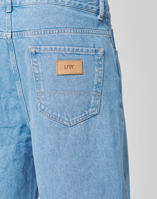 Close-up of the back pocket on light blue LFDY Wide Denim jeans with a tan leather patch above the pocket featuring the LFDY logo.