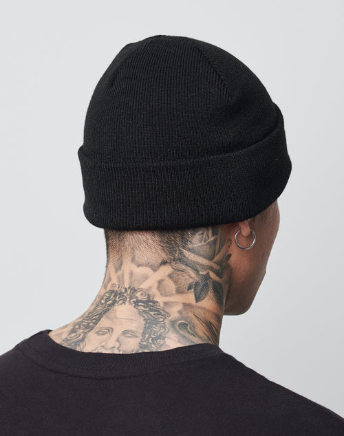 A person is shown from behind wearing an LFDY Beanie by LFDY and a Regular Fit black shirt. They have neck tattoos, including a detailed face and rose, and wear a hoop earring in their left ear.
