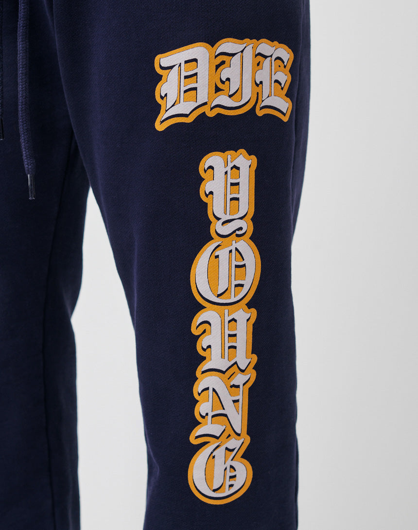 Close-up of navy blue Live Fast Sweat Jogger pants by LIVE FAST DIE YOUNG in 100% Baumwolle, featuring bold yellow and white outlined DIE YOUNG text running vertically down the leg. Regular fit for everyday wear.