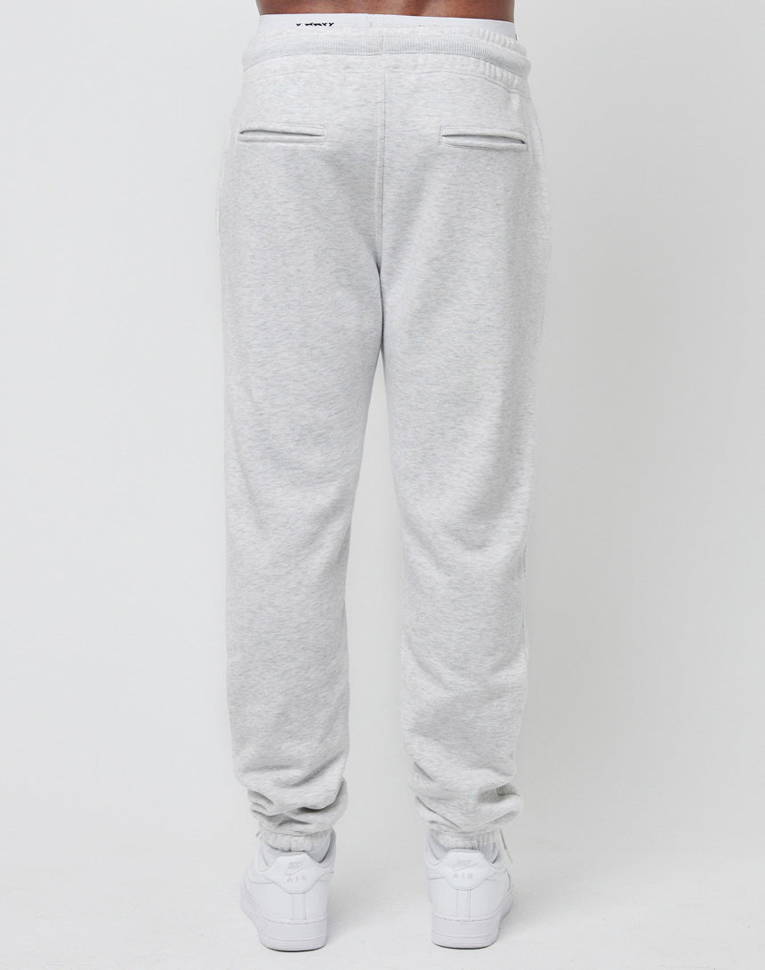 Model wears LIVE FAST DIE YOUNG DY Sweat Jogger in light gray, Regular Fit, featuring two back welt pockets and an elastic waistband. Paired with white sneakers, shown from the back against a plain white background.