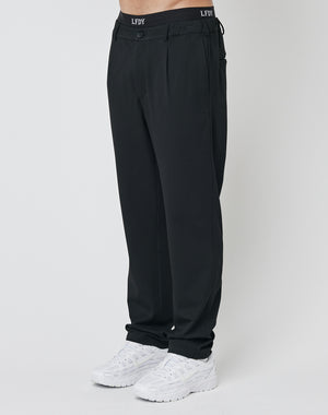 A person wears Regular Casual Pants from LFDY with an elastic waistband and white sneakers, standing against a plain white background. The photo displays the regular fit trousers from waist to feet.