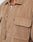 Close-up of a person wearing the LFDY Corduroy Shacket in tan Regular Fit with buttons, front pocket featuring a small fabric tag, and part of a white shirt visible underneath.