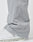 Close-up of a person wearing LFDY Calf Zip Pants in light gray nylon with an elastic waistband, drawstring, and ankle zipper detail, partially covering white sneakers against a plain white background.