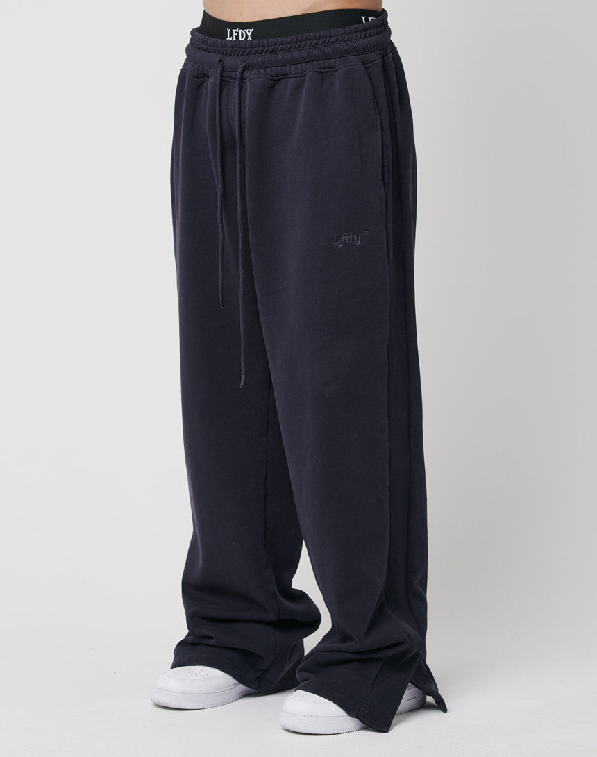 Model wears LFDY Wide Jogger 2.0 in loose-fitting dark navy cotton with drawstring waist, subtle logo, wide fit and slight flare, paired with white sneakers against a plain white background.