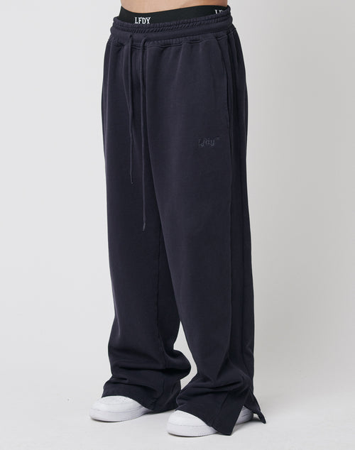 Model wears LFDY Wide Jogger 2.0 in loose-fitting dark navy cotton with drawstring waist, subtle logo, wide fit and slight flare, paired with white sneakers against a plain white background.